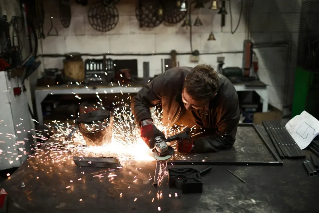 A fabricator cutting a piece of metal with sparks flying