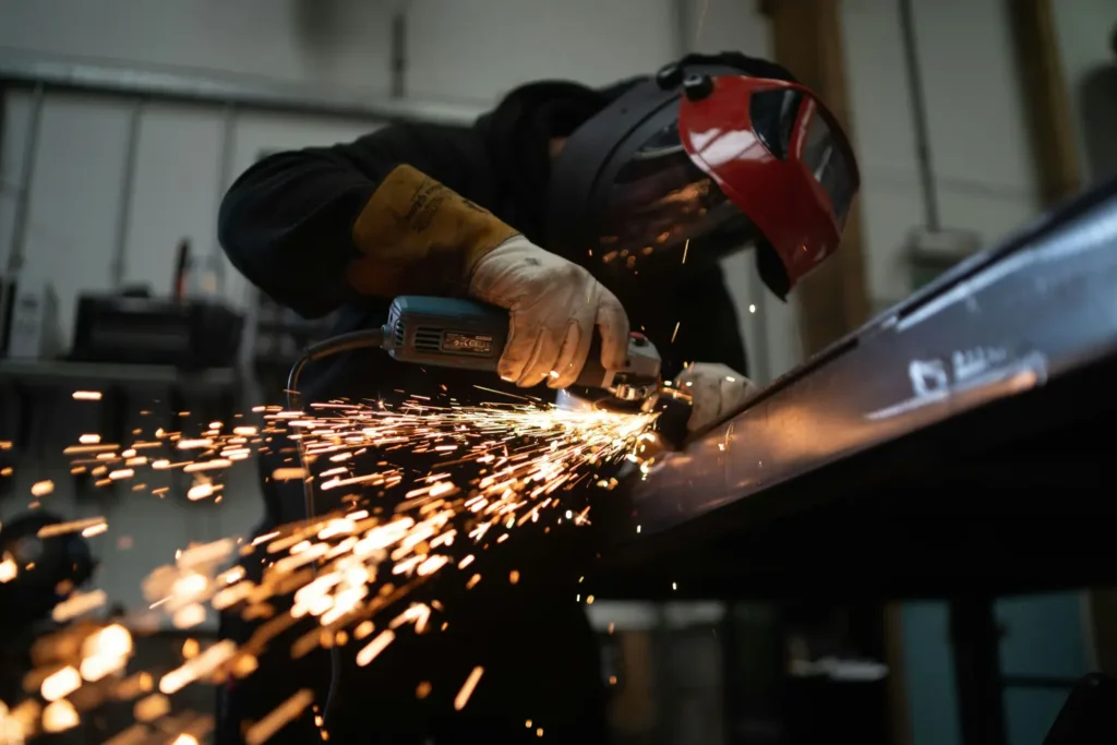 Metal worker cutting steel beam with sparks flying